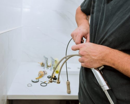 Work in a bathroom plumber holding a faucet plumbing assemble repair service